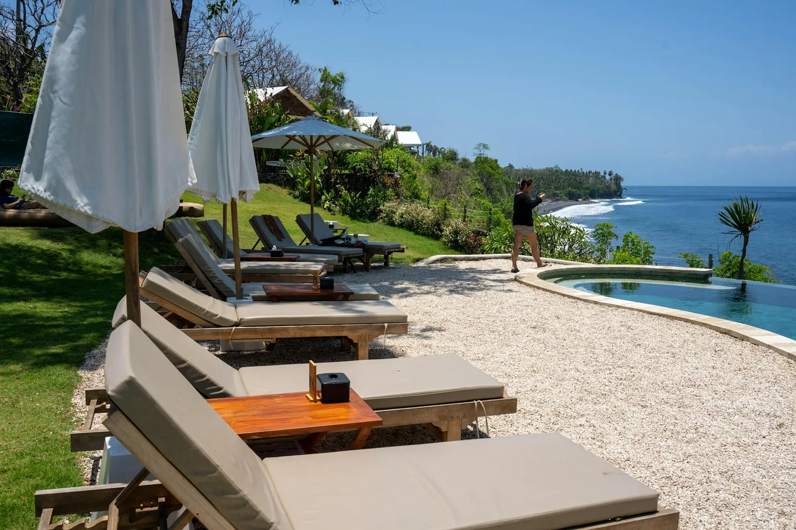Sun loungers beside a clifftop infinity pool overlooking the ocean in South Lombok.