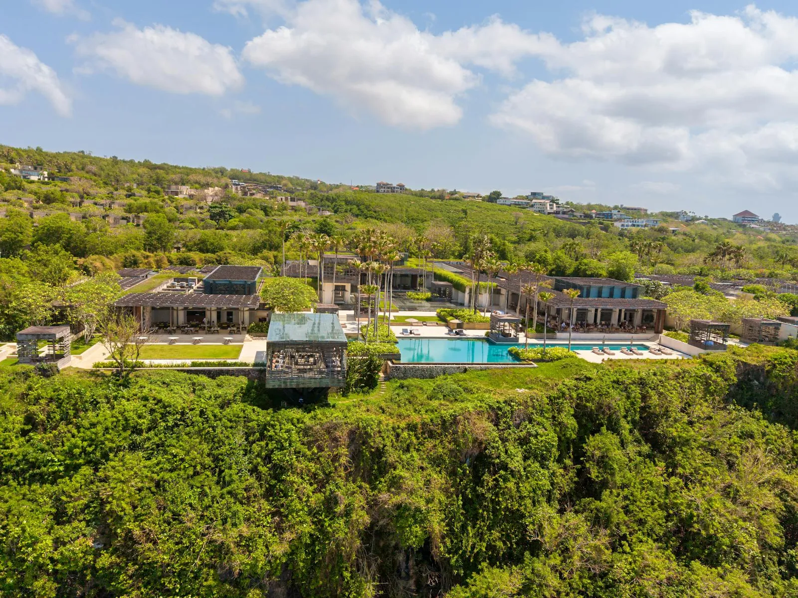 Aerial view of a clifftop villa and resort complex with pools above the South Lombok coast.
