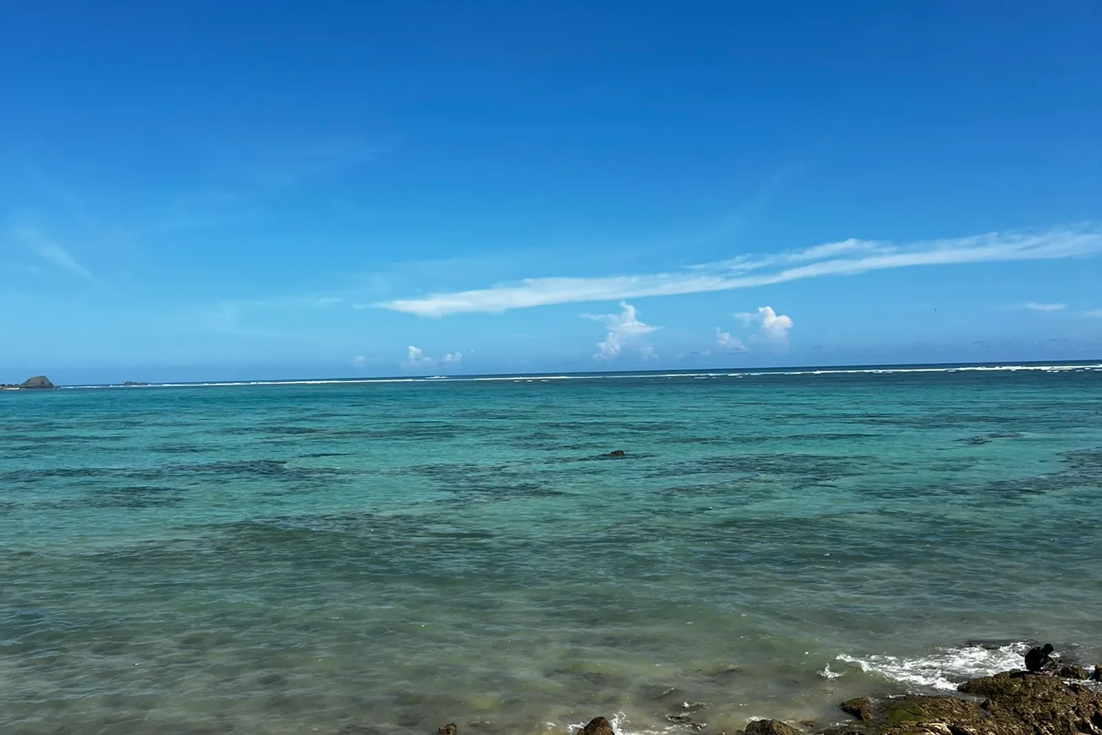 Clear turquoise water and a rocky shoreline on the Kuta coast, South Lombok.