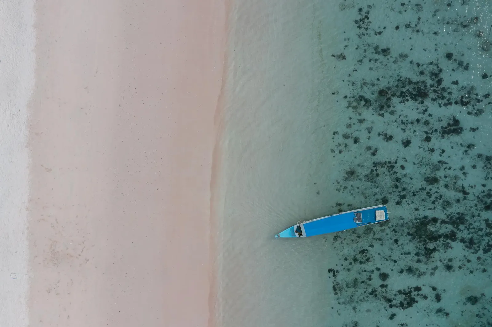 Traditional outrigger fishing boats on a clear-water beach in the Mawun area, South Lombok.